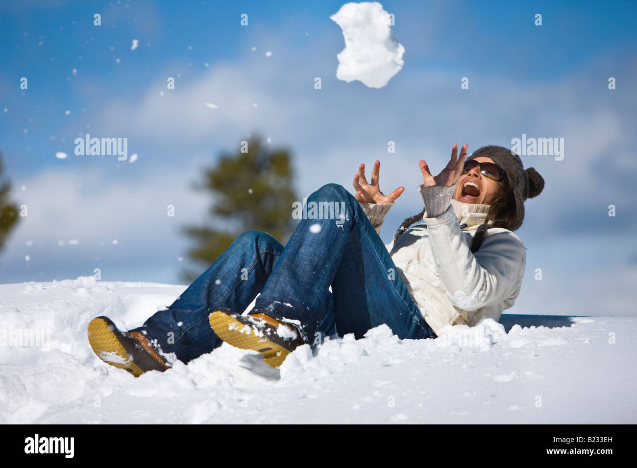 Una chica americana se ríe como ella trata de atrapar a una gran bola de nieve cerca de Jackson Hole, Wyoming, Estados Unidos. Foto de stock