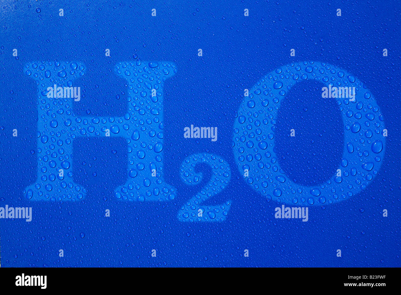 H2O símbolo de texto gotas de agua sobre fondo azul. Foto de stock