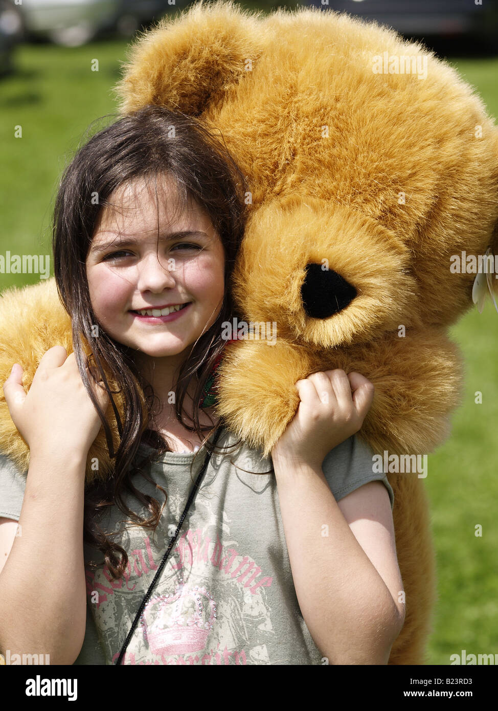 Brown joven pelirroja Chica sujetando un oso de peluche gigante que había traído en un coche venta de arranque Foto de stock