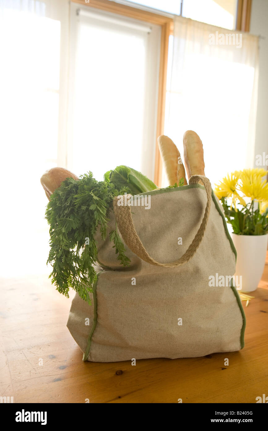 Bolsas de la compra reutilizables lleno de comida en la mesa con la brillante luz de la ventana Foto de stock