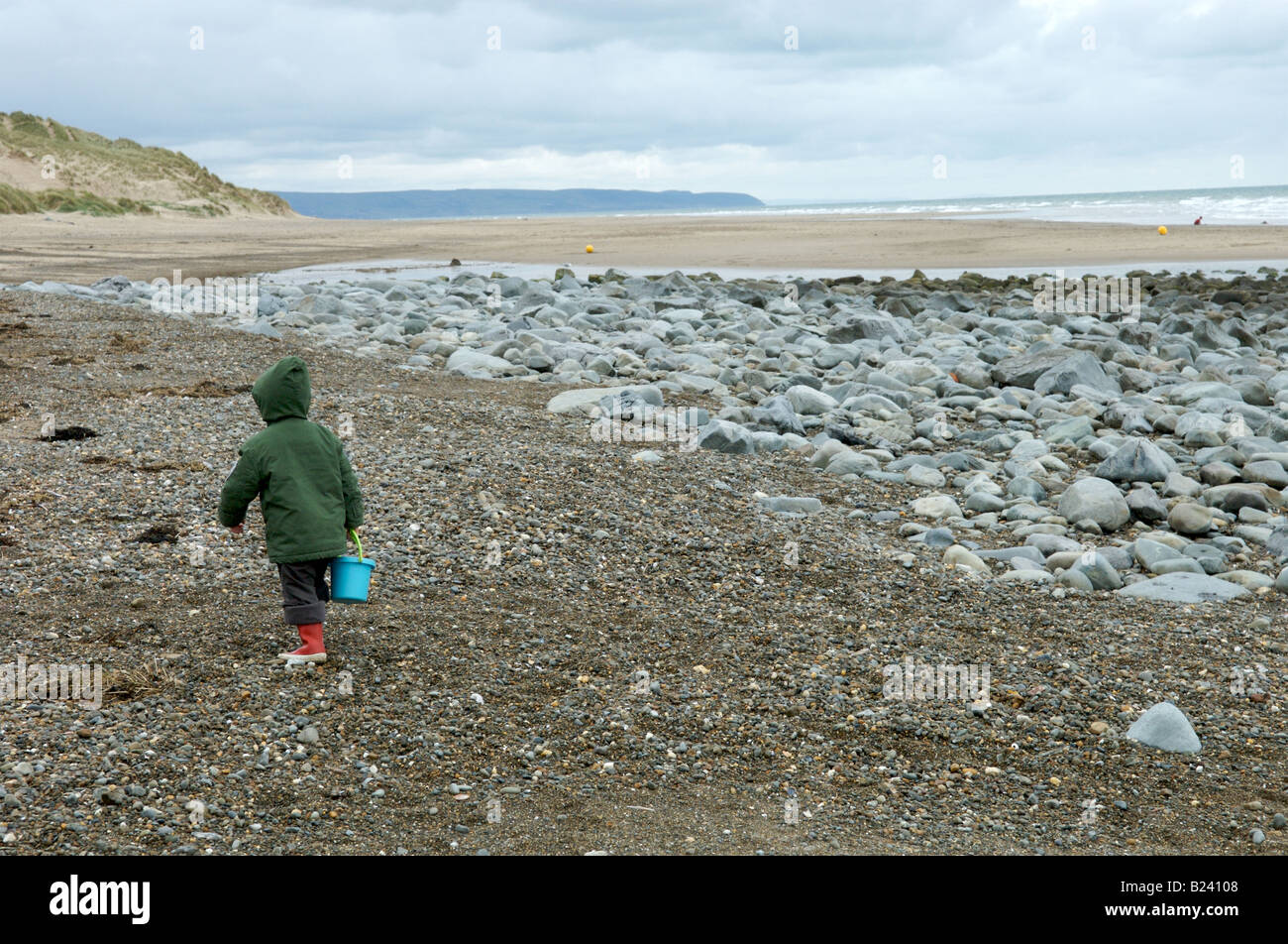 Un chico en la playa recogiendo conchas Foto de stock