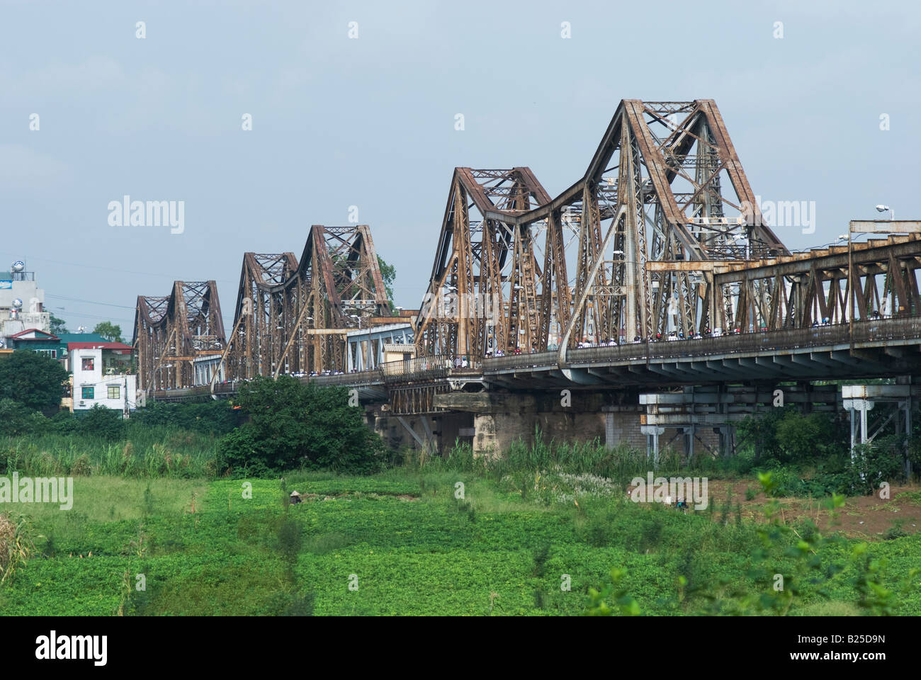 La larga bien puente ferroviario cruzando el Río Rojo de Hanoi visto desde la isla en el río Foto de stock