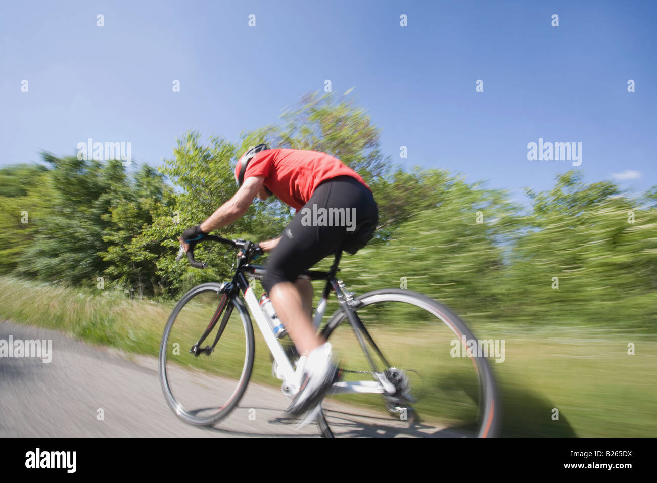 Vista lateral de un ciclista ciclismo en carretera, movimiento borrosa Foto de stock