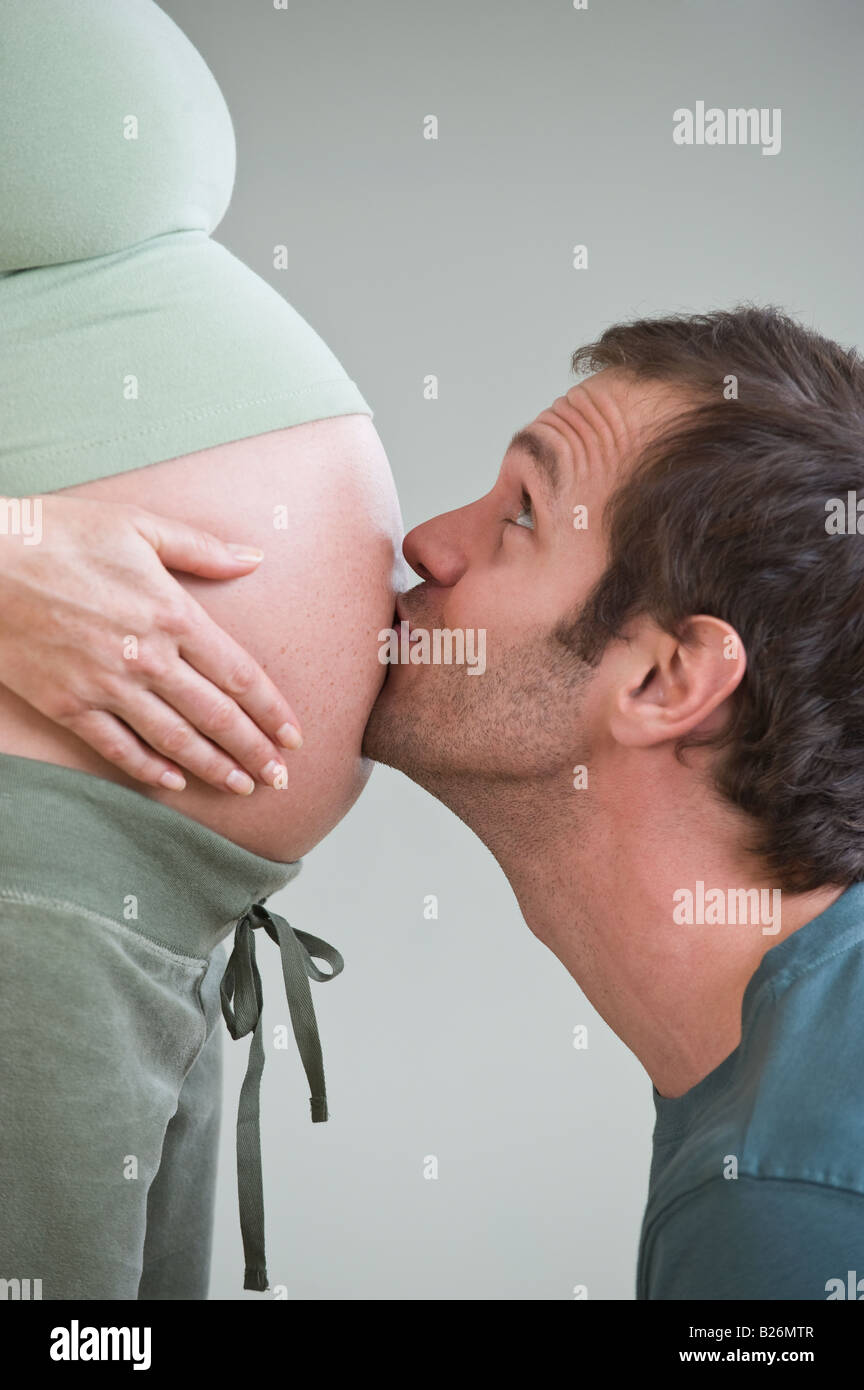 Hombre hispano besar la esposa embarazada vientre Foto de stock