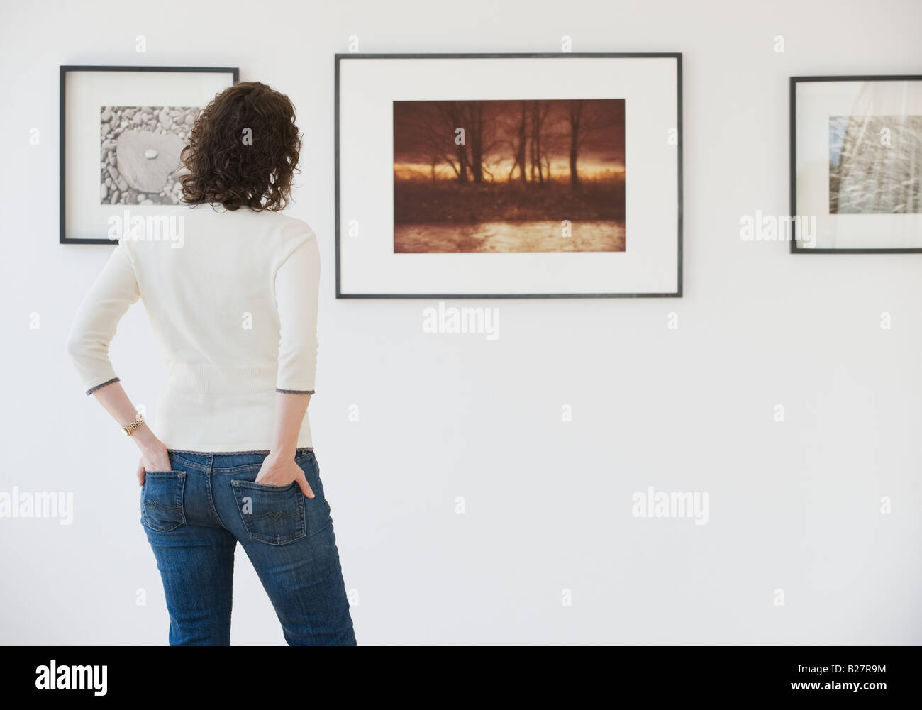 Mujer mirando su arte en la galería de arte Foto de stock
