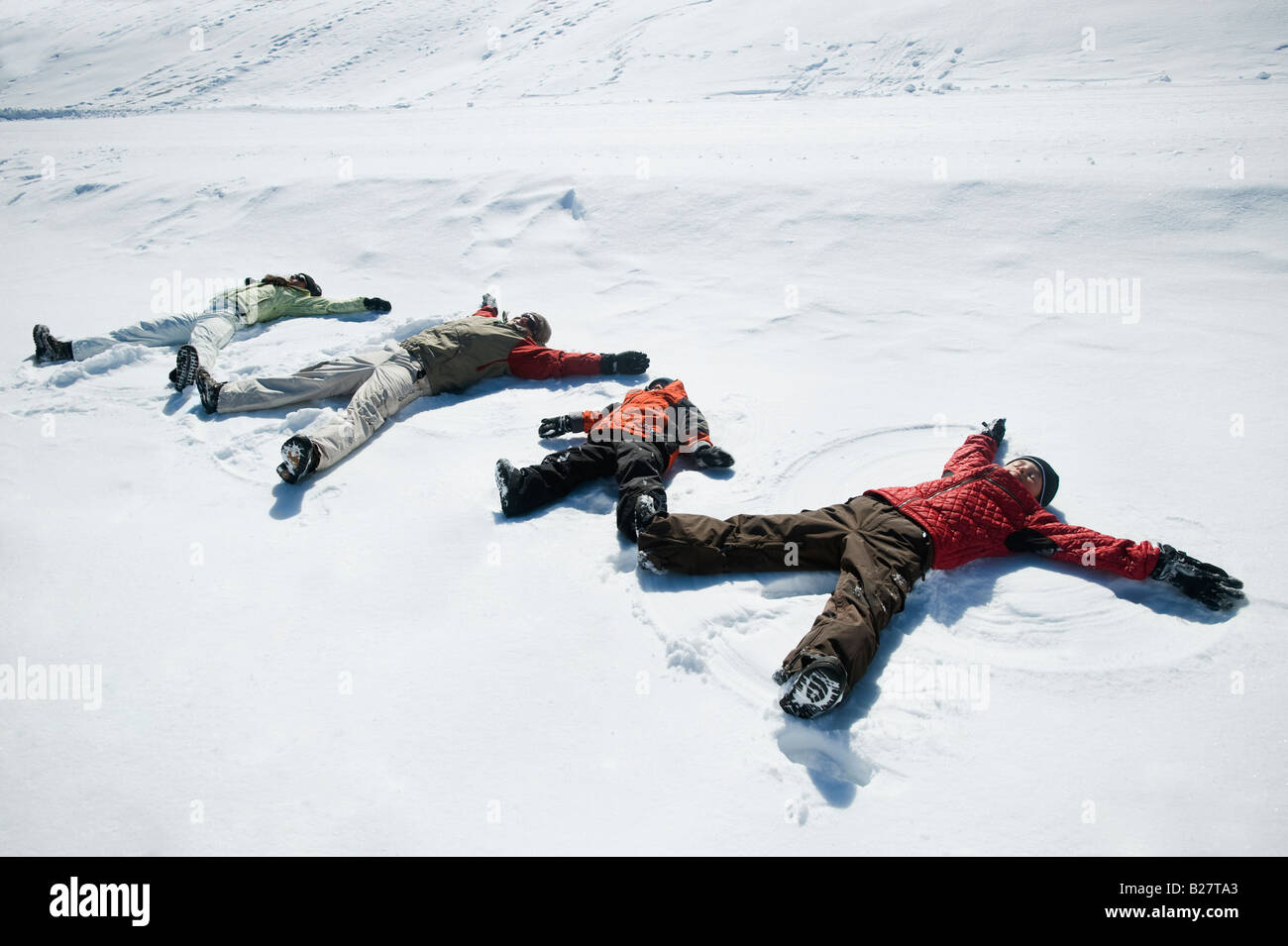 Familia haciendo ángeles de nieve Foto de stock