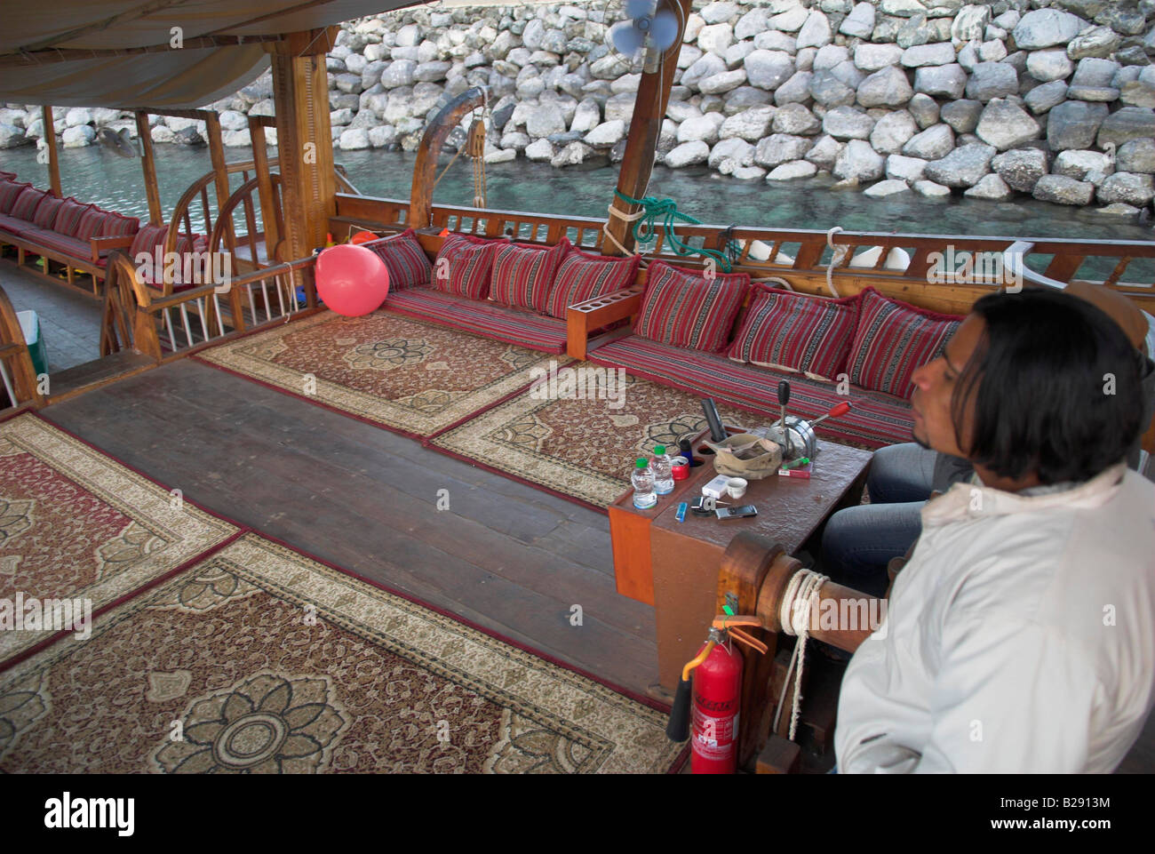Joven al timón de un dhow Marina Bander Ar Rawdah cerca de Muscat, Omán Foto de stock