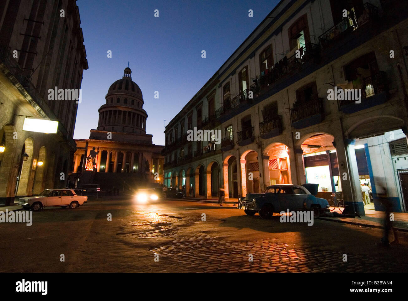 Rundown oscura calle con vista hacia el Capitolio edificio colonial en La Habana Vieja, La Habana, Cuba Foto de stock