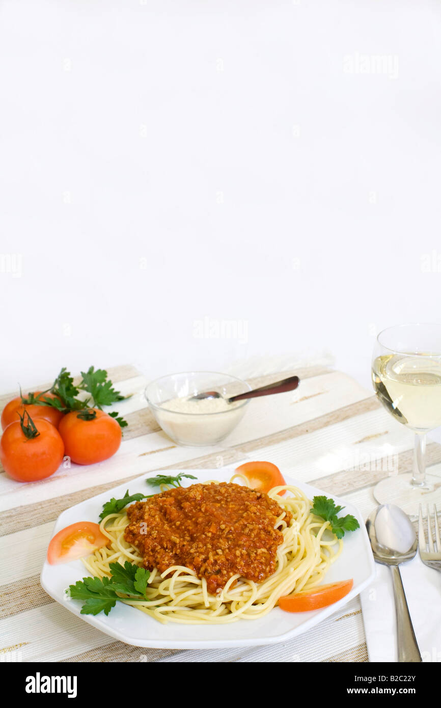 Los espaguetis a la boloñesa con queso parmesano en un tazón, vino blanco, los tomates Foto de stock