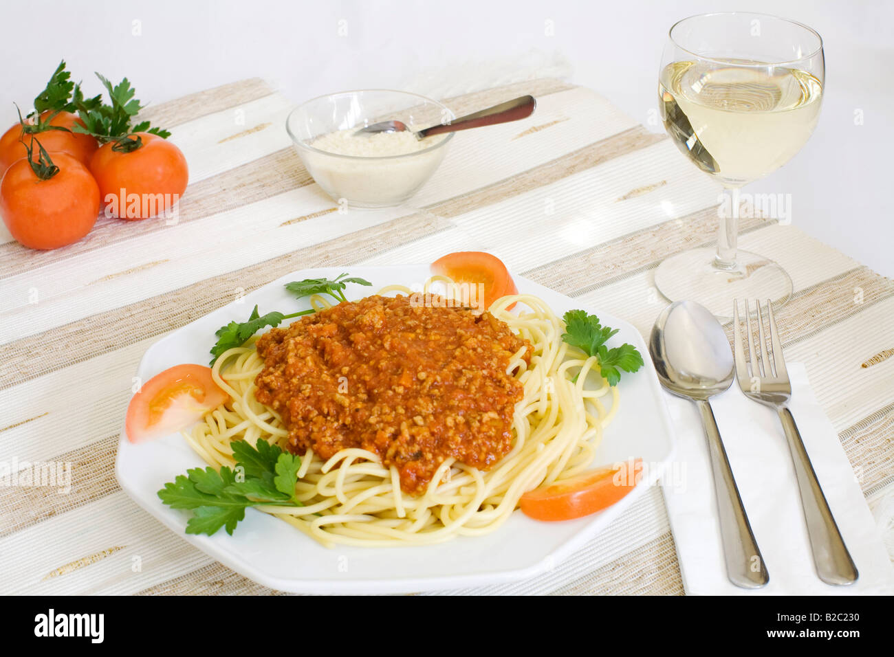 Los espaguetis a la boloñesa con queso parmesano en un tazón, vino blanco, los tomates Foto de stock