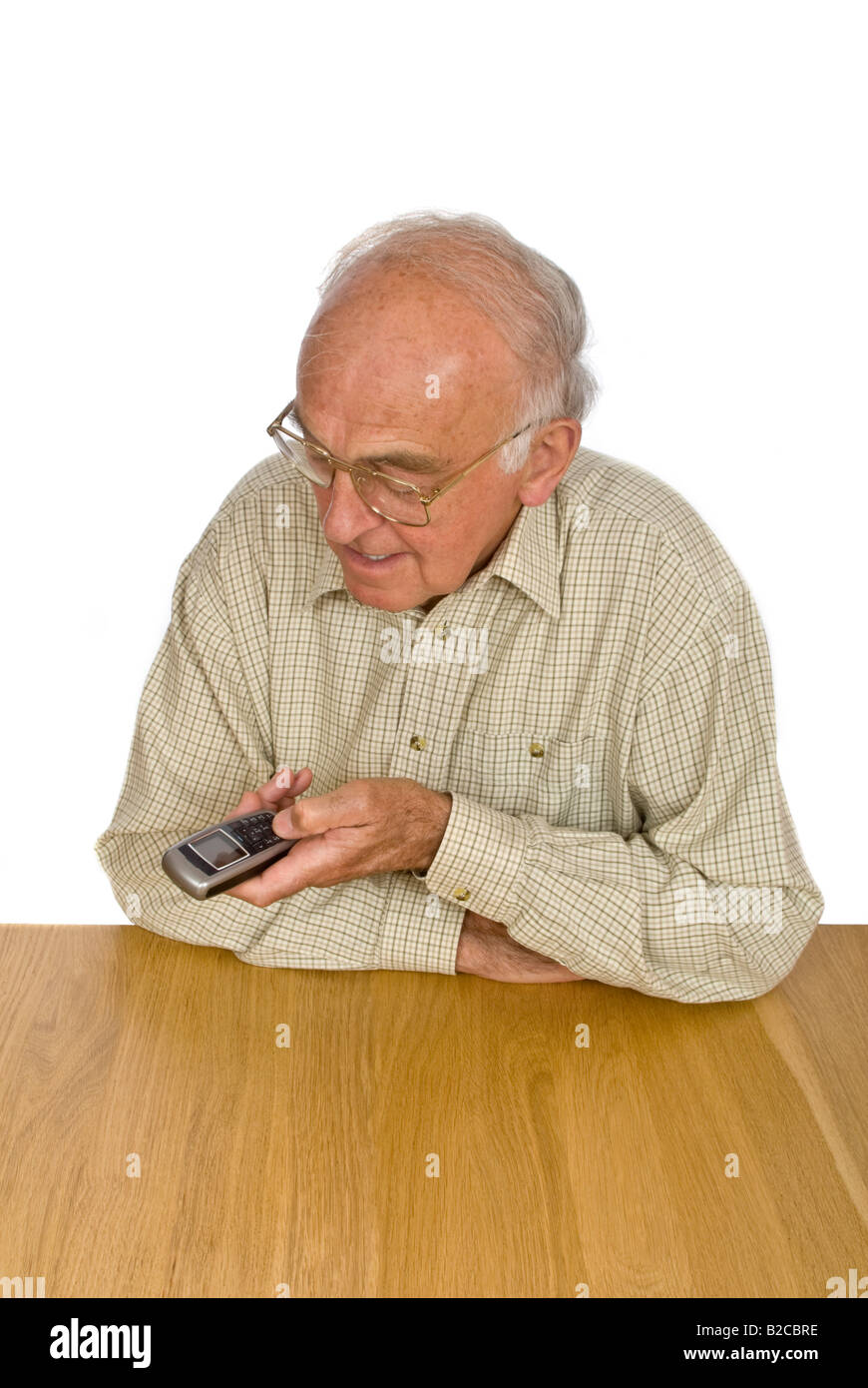 Vertical de un anciano caballero tiene dificultad para ver y utilizar los botones pequeños en un teléfono móvil. Foto de stock