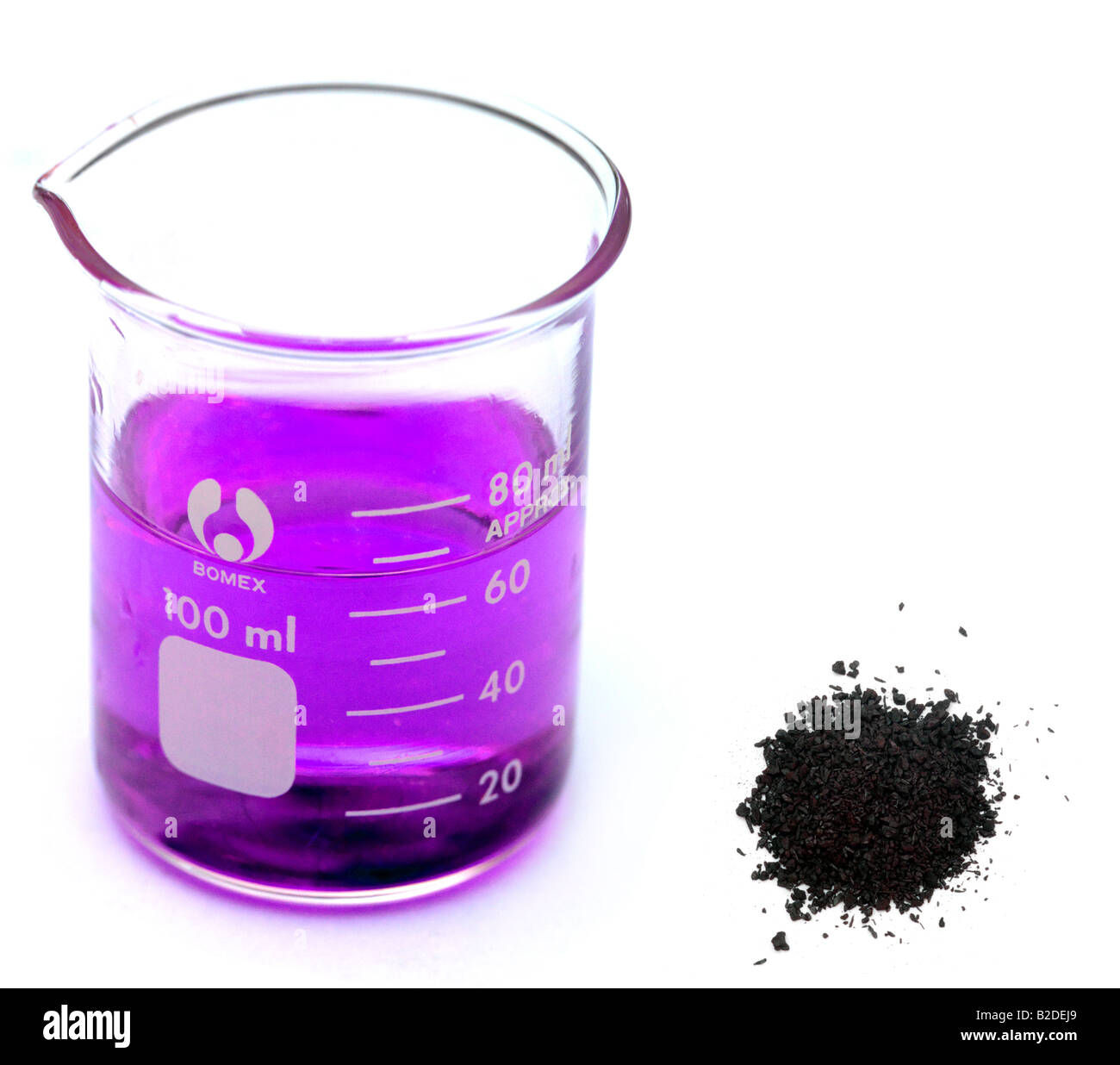 Cristales de permanganato de potasio y un vaso que contenga la solución de permanganato de Cristales de permanganato de potasio y un vaso que contenga la solución de permanganato de