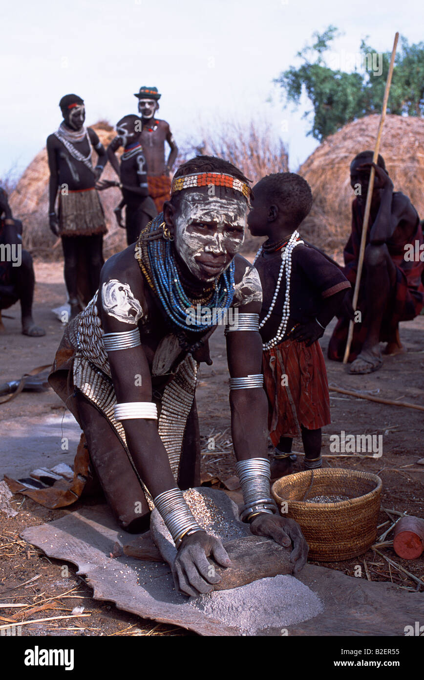 una-mujer-nyangatom-muele-sorgo-con-dos-piedras-tipicas-de-su-tribu-viste-un-fuertemente-bordada-falda-de-vaca-b2er55.jpg