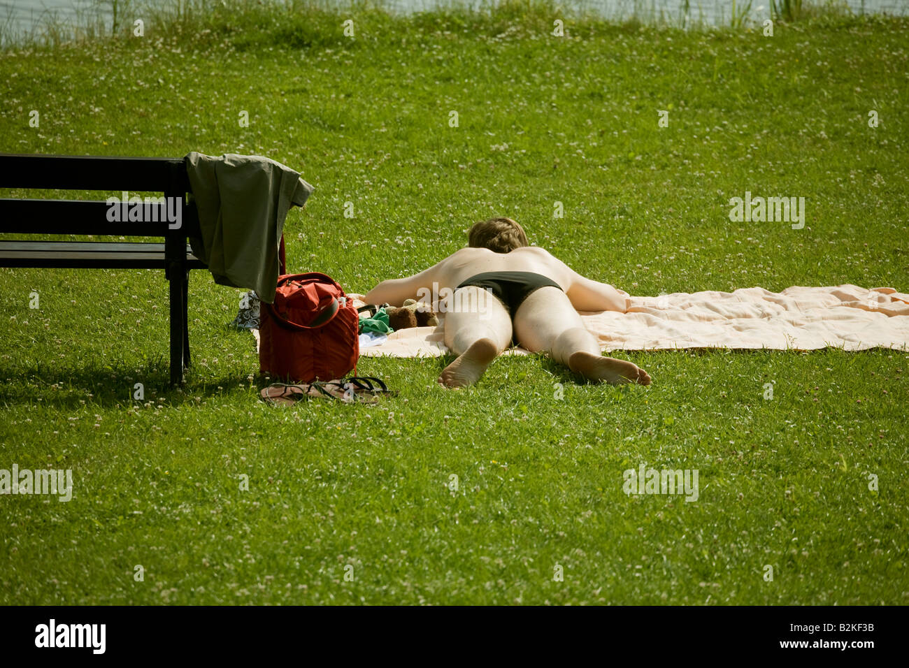 Un hombre joven sunbathes en una pradera a orillas de un lago Foto de stock
