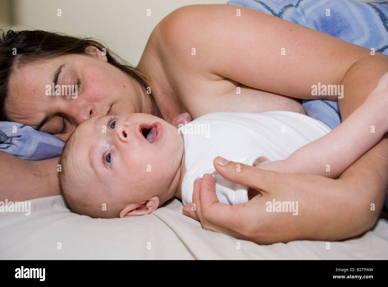 Bostezo Baby Boy Josué Kailas Hudson de 15 semanas de dormir en la cama con la madre Deborah aguas Foto de stock