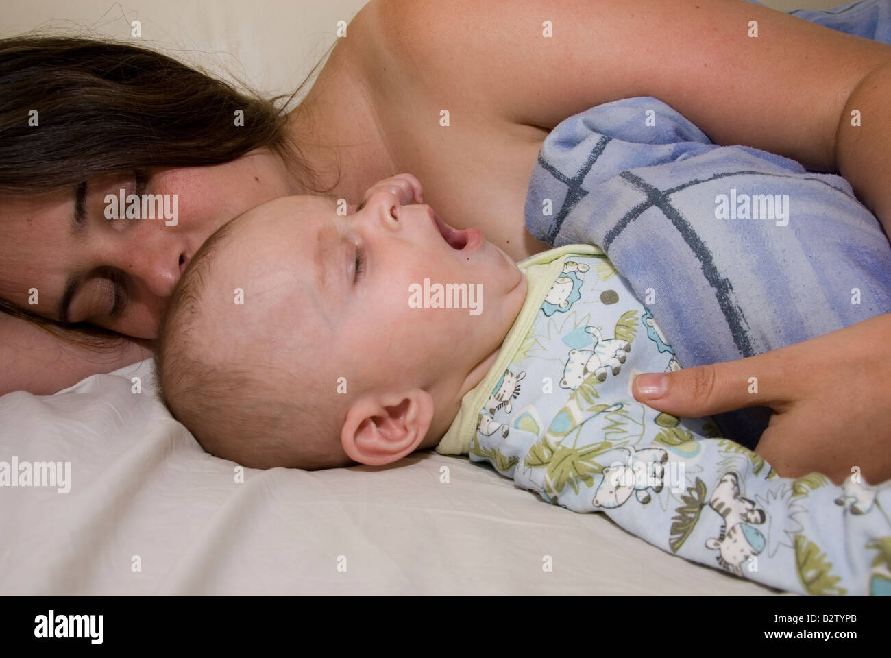 Bostezo Baby Boy Josué Kailas Hudson de 15 semanas caricias duermen en la cama con la madre Deborah aguas Foto de stock