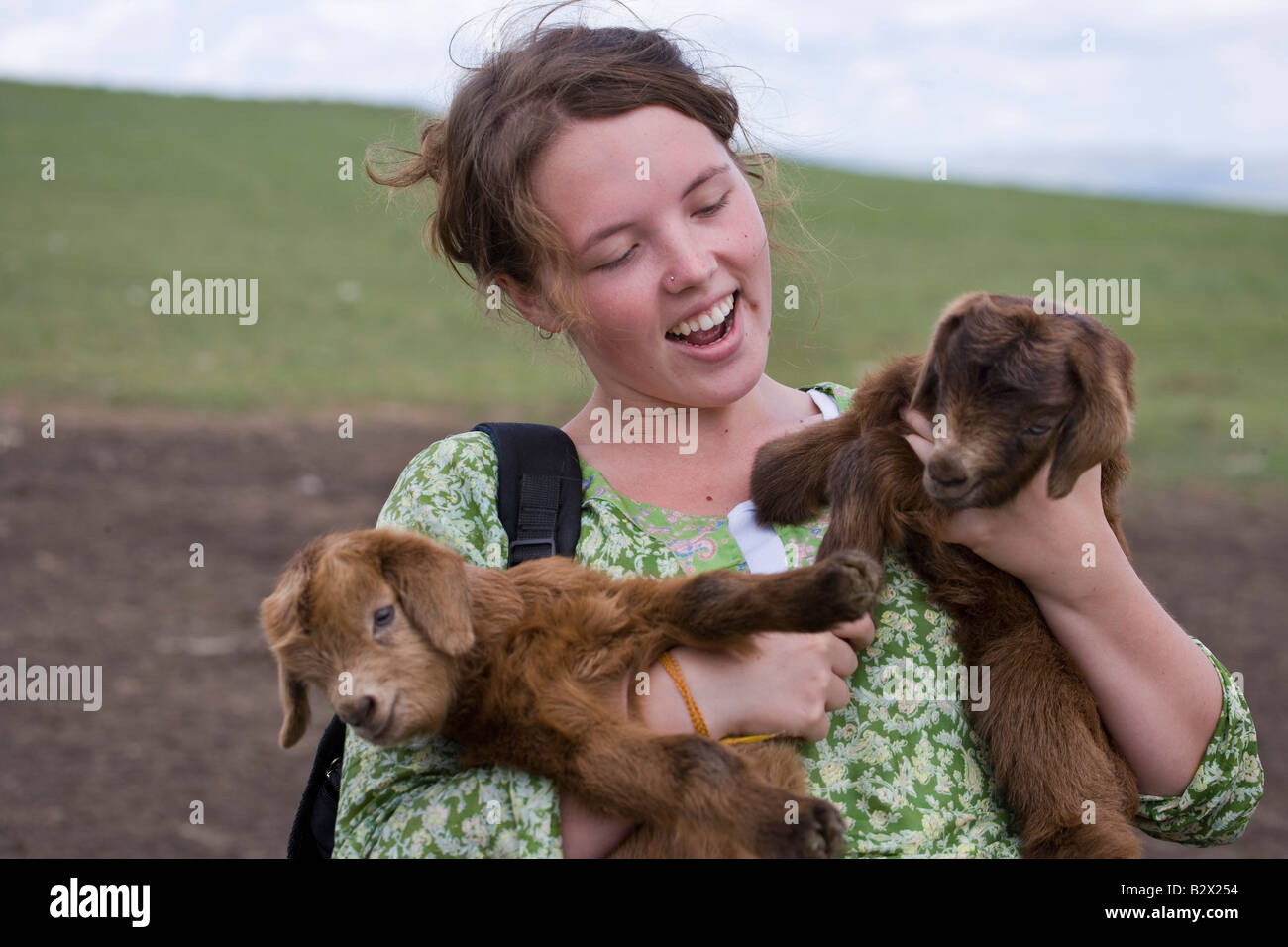Mochilero femenino la celebración de dos cabras bebé en una visita a un ger Foto de stock