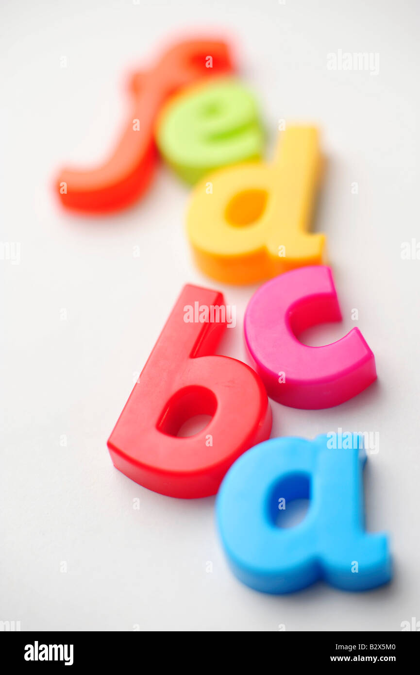 Cartas de plástico coloreado deletrear abcdefg para ilustrar el aprendizaje del alfabeto Foto de stock