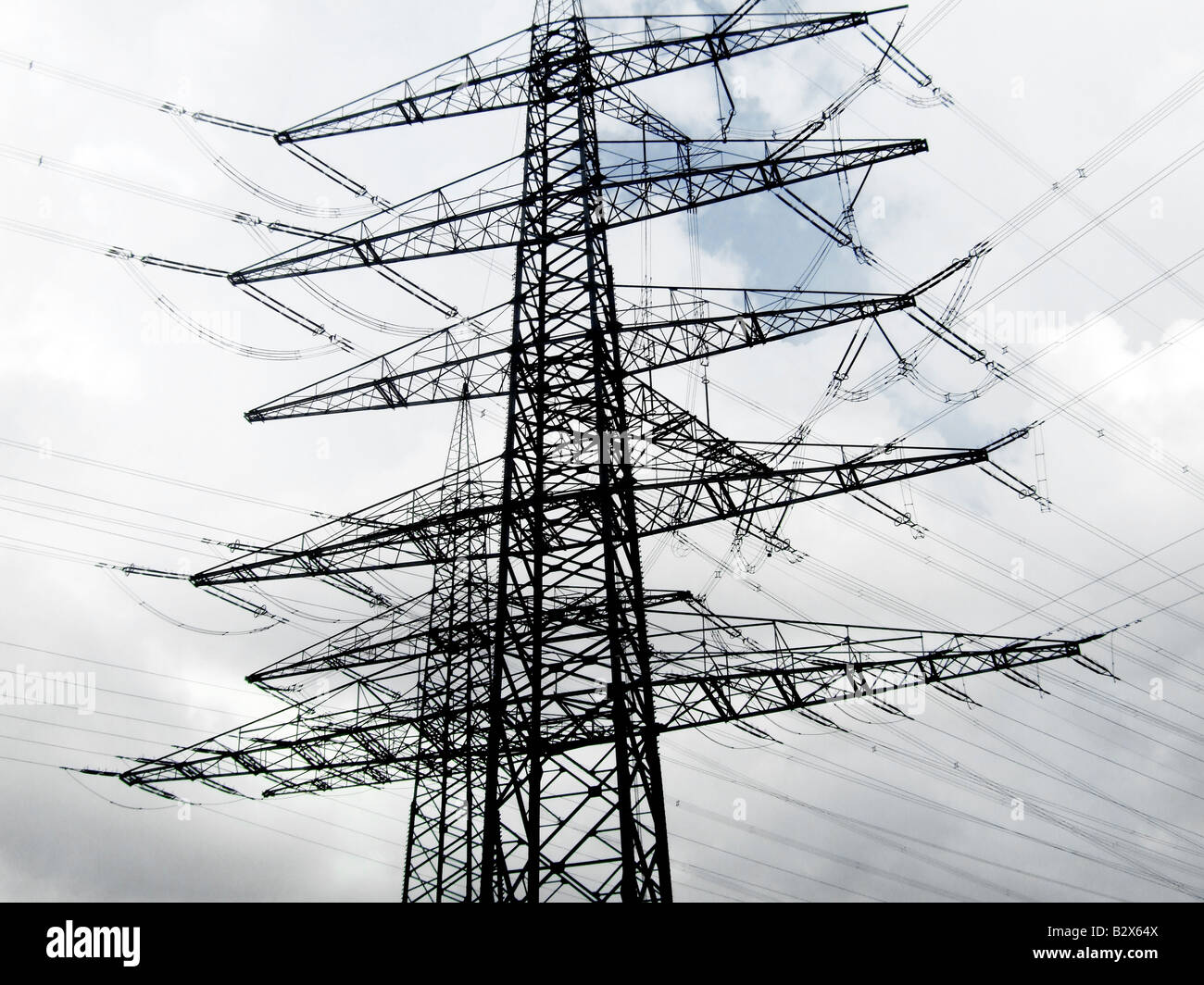 Cables de alimentación de electricidad de alta tensión y pilón contra nubes iluminadas Foto de stock