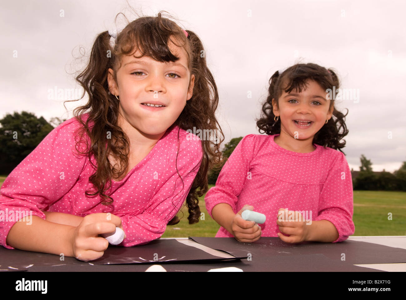 Izquierda de 6 años y 4 año de edad hermanas en una comunidad al aire libre diversión día Hanworth Middlesex UK Foto de stock