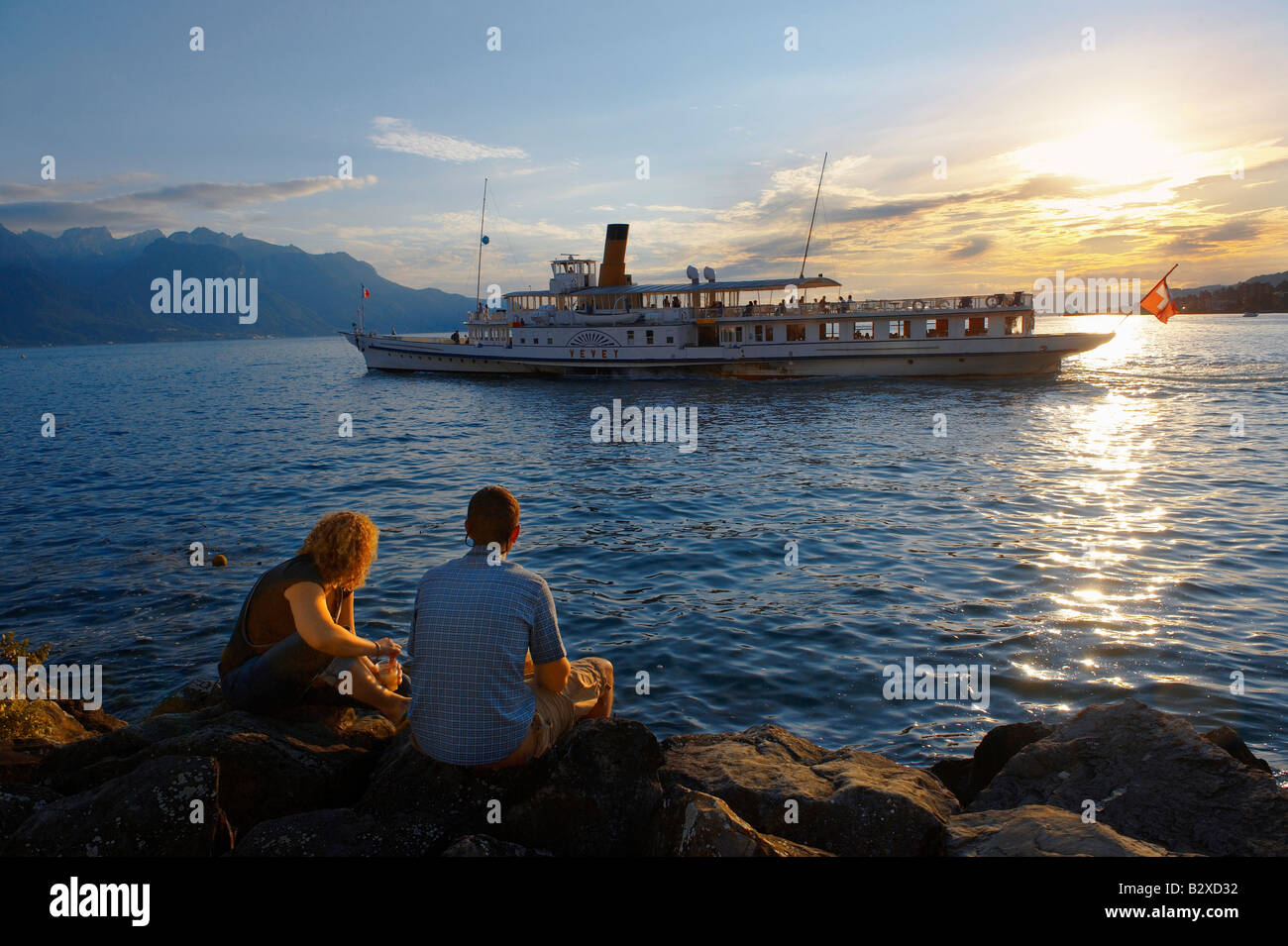 Pareja joven busca en un barco de pasajeros en el Lago Leman al atardecer, Montreaux, Suiza Vaud Foto de stock