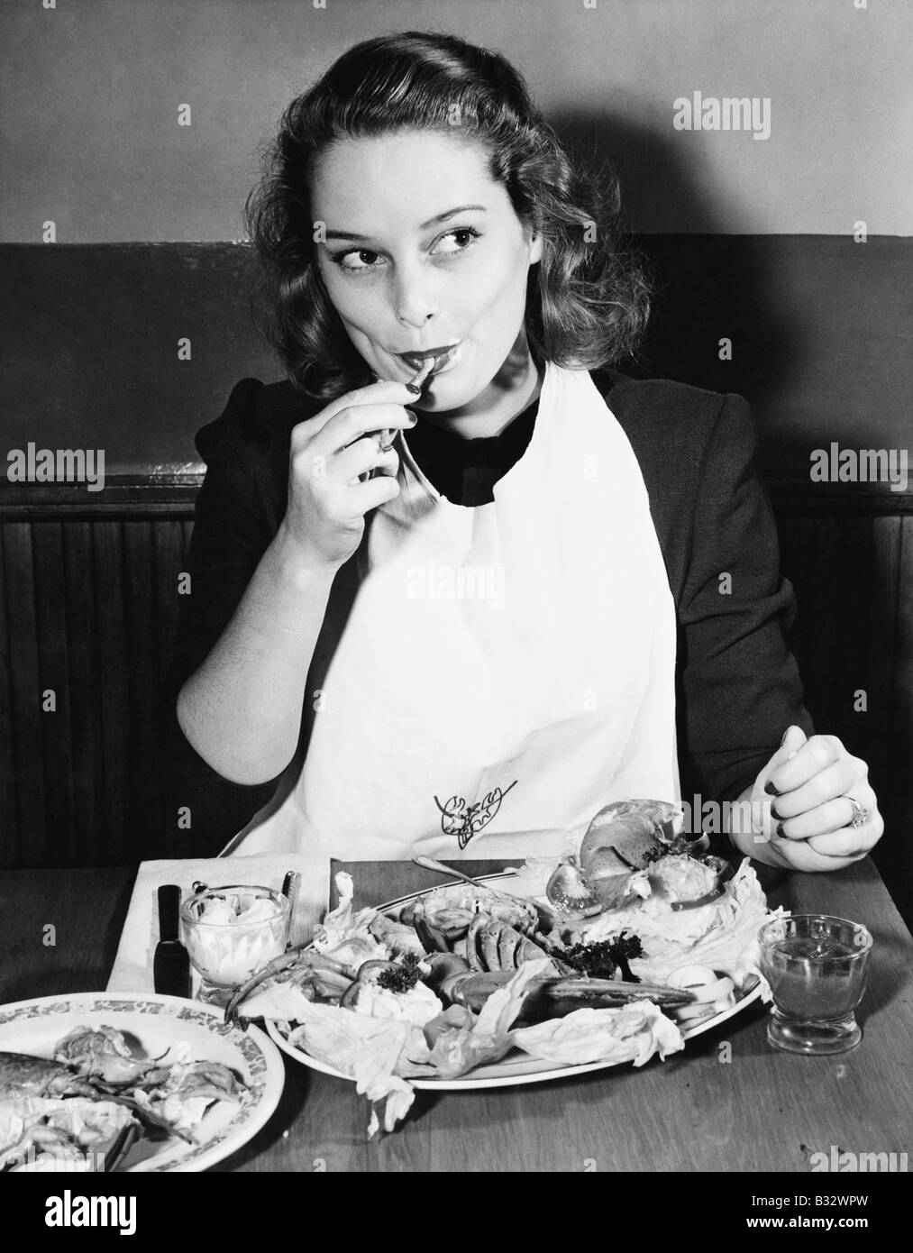 Mujer joven con un babero comiendo Langosta Fotografía de stock - Alamy