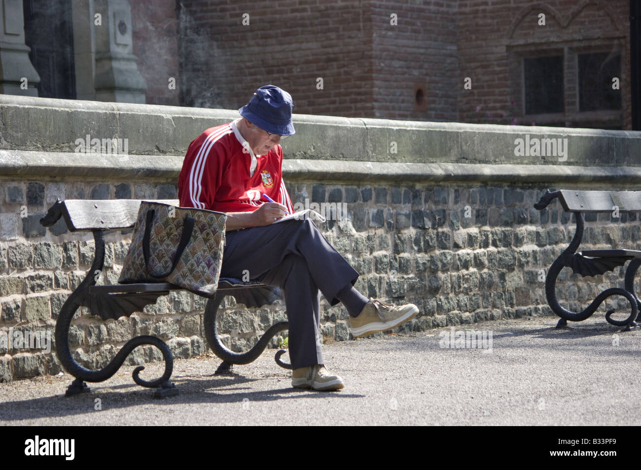 Viejo hombre sentado en un banco en un parque haciendo un crucigrama  Fotografía de stock - Alamy