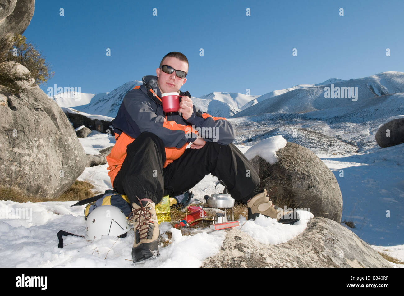 Un cansado excursionista invernal se relaja con una bebida caliente Foto de stock