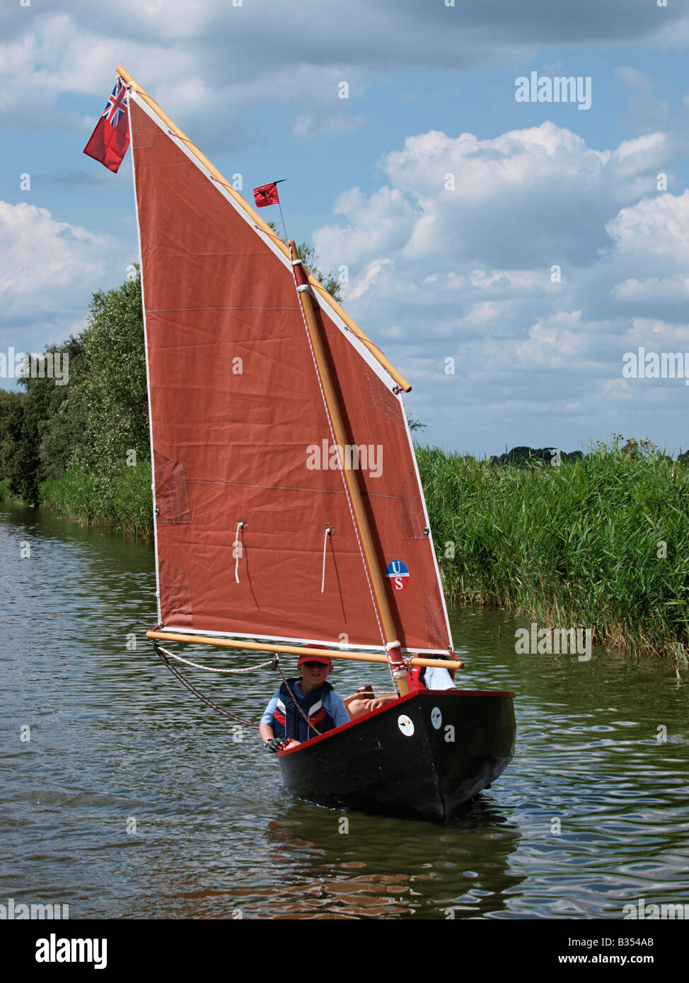 Los niños en vela lancha flotante sobre el río thurne Norfolk Broads Inglaterra Foto de stock