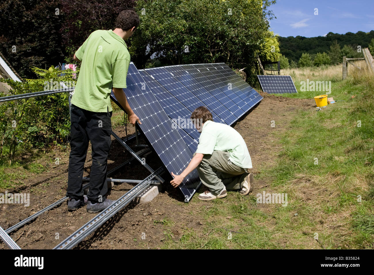 Dos trabajadores de instalar paneles solares PV sobre un bastidor galvanizado en campo Cotswolds UK Foto de stock