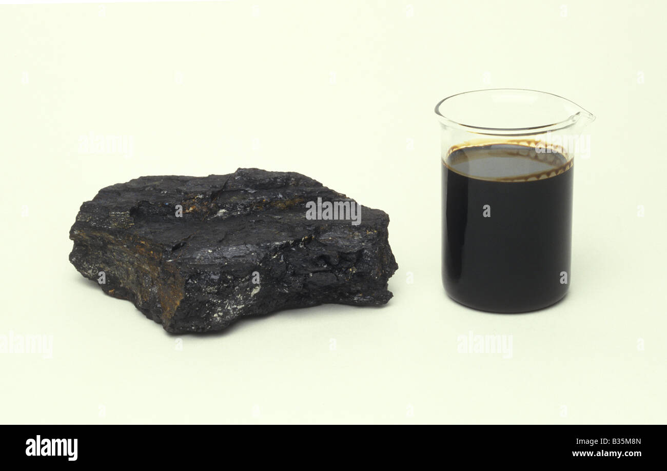 Un trozo de carbón al lado de un vaso de aceite Foto de stock
