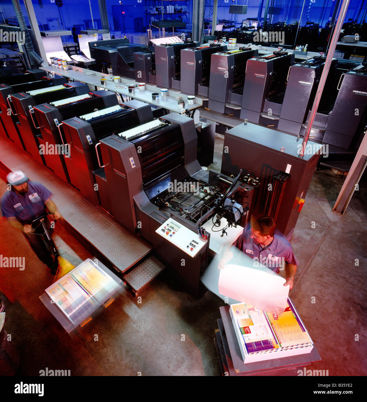 Los trabajadores ejecutando una prensa Heidelberg en una planta de litografía Foto de stock