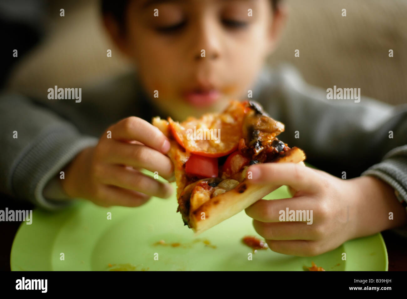 Pizza casera muchacho de seis años se introduce en un segmento de su madre s home cooking mestizos étnicos indios Foto de stock