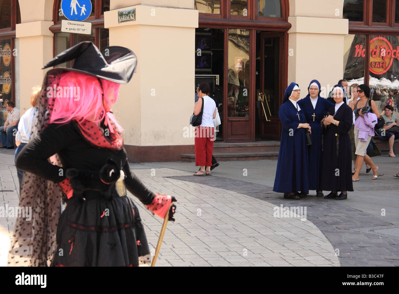 Animador de la calle vestida como una bruja, observados por las monjas en el Rynek Glowny (plaza del mercado), Cracovia, Polonia Foto de stock