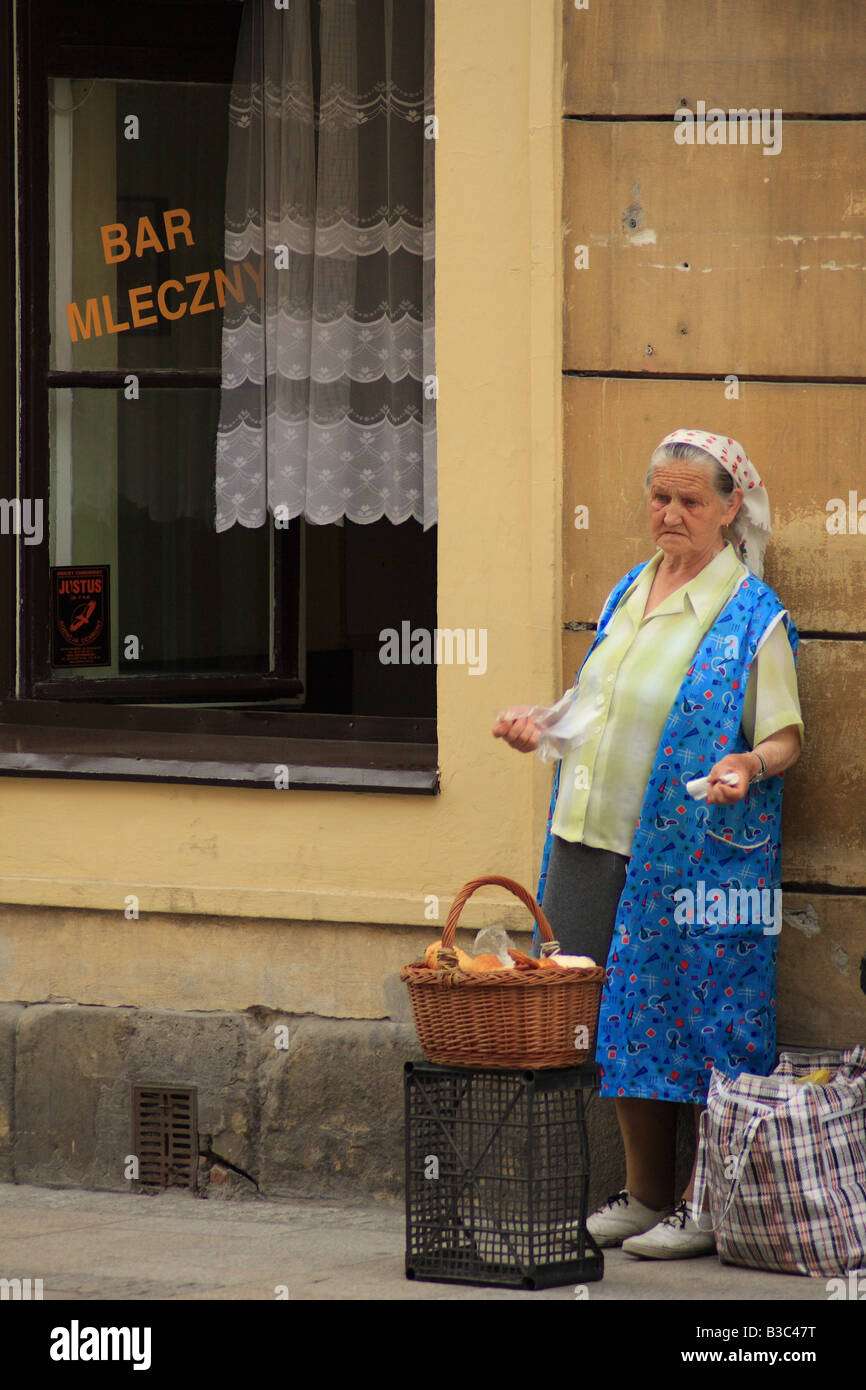 Anciana vendiendo pan en la calle outsie Pod temida milk bar (bar Mcleczny) en Cracovia, Polonia Foto de stock