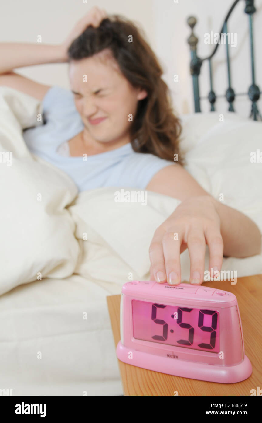 Una ni a despierta en la cama por su reloj de alarma Fotograf a de
