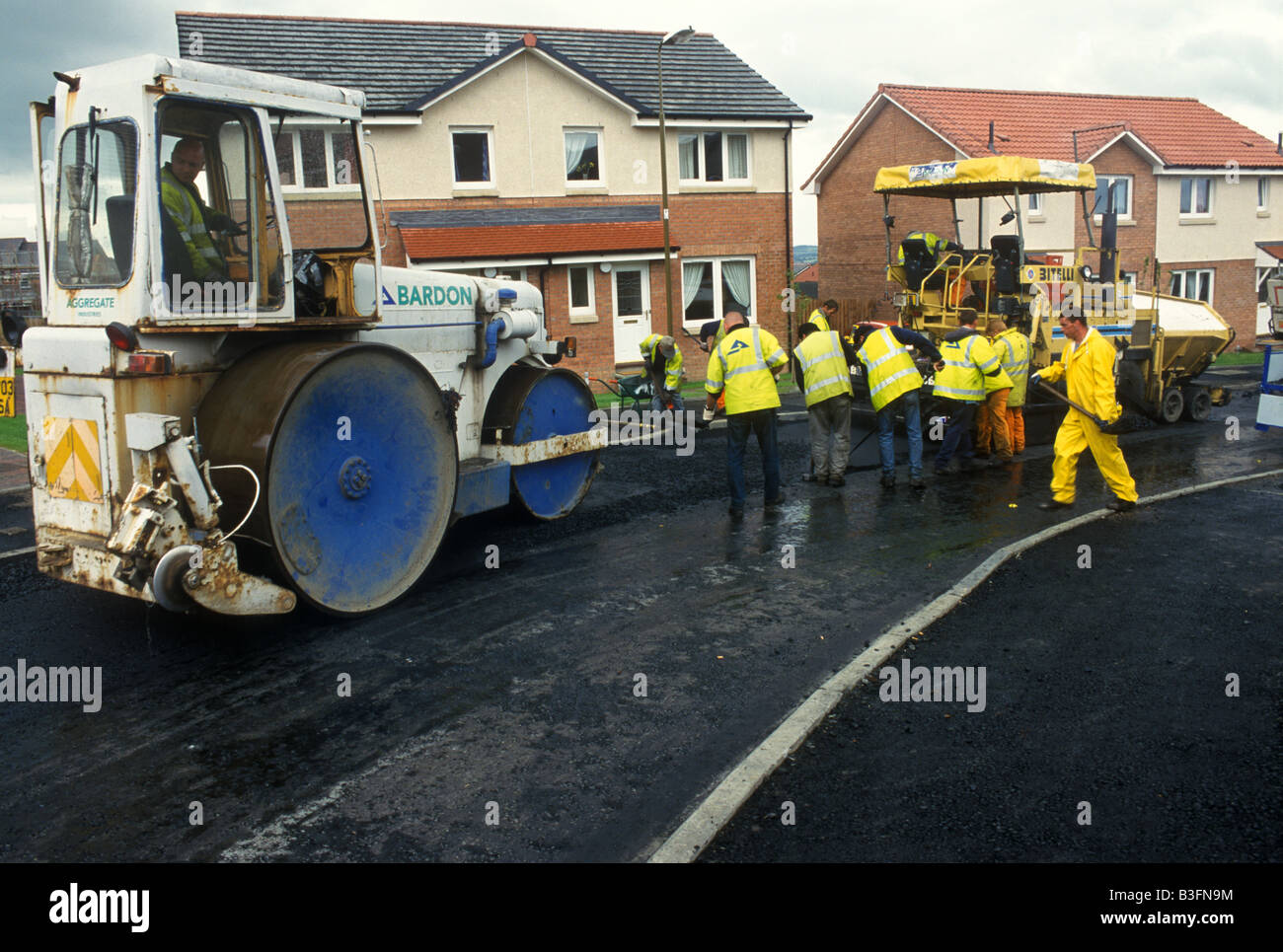 Pista de obreros revestir una carretera utilizando un rodillo de vapor Foto de stock