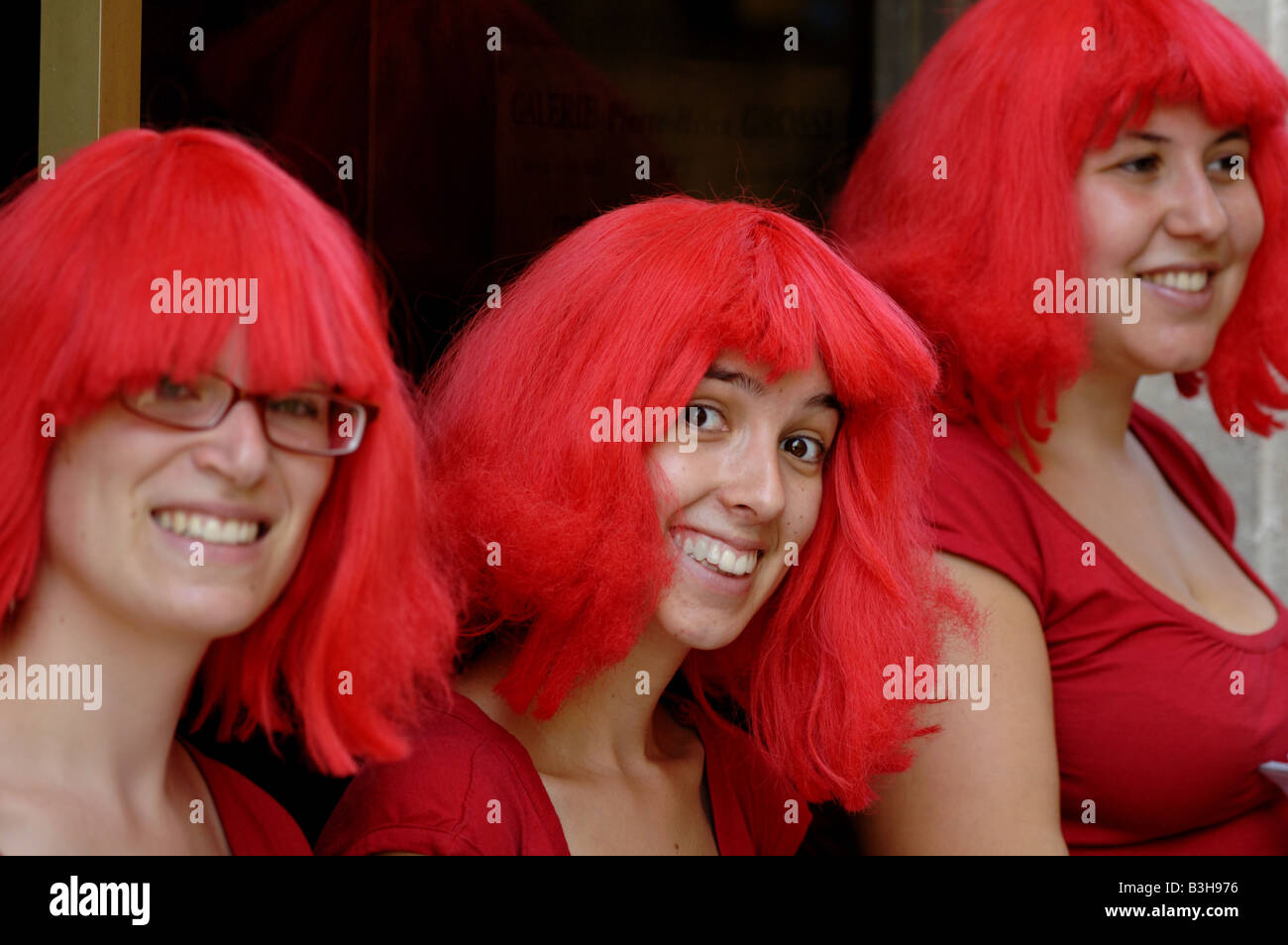 Tres señoritas sonrientes vestidas de rojo en Avignon, Francia. Foto de stock