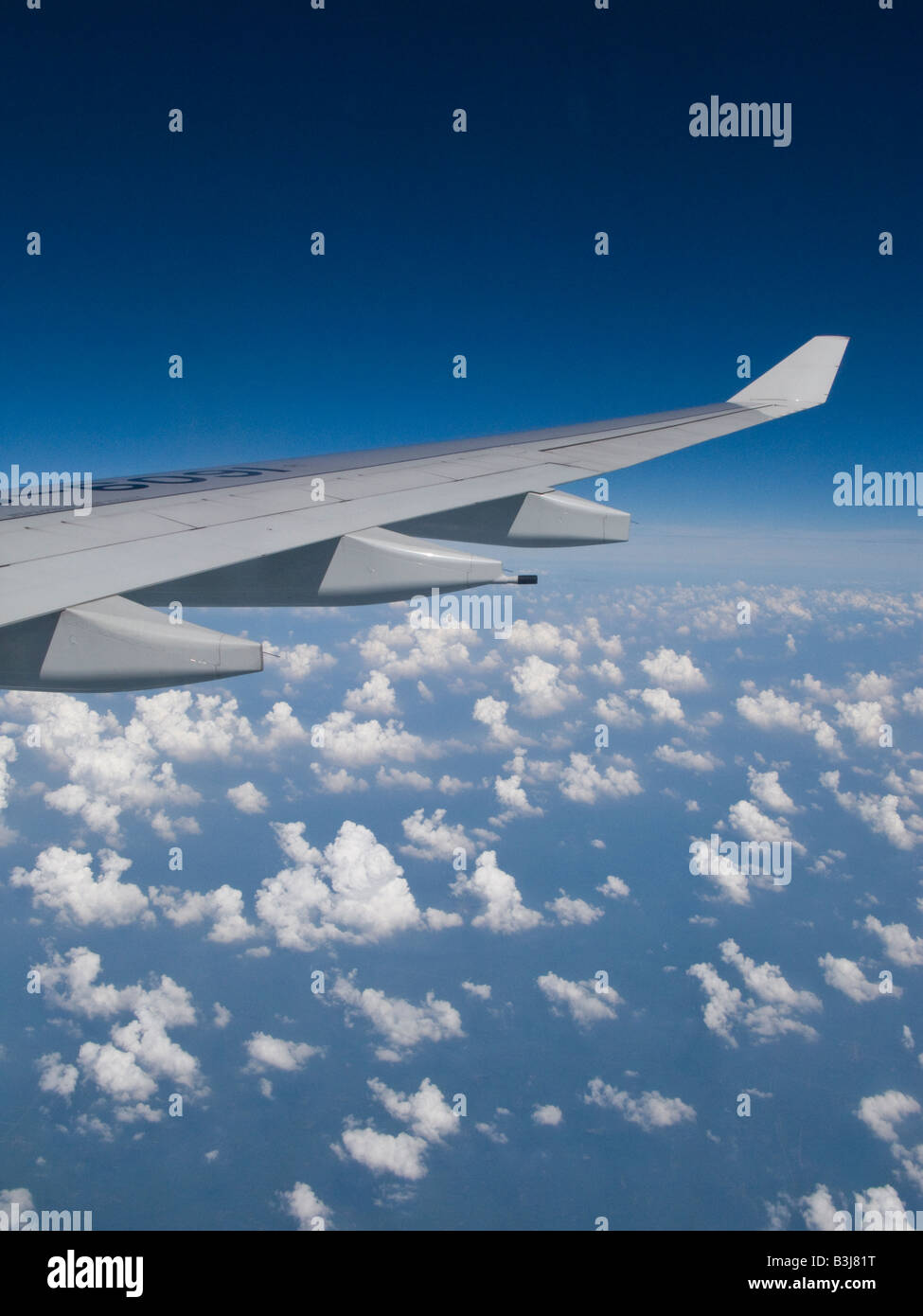 Ala de avión a través de un azul cielo nublado tomadas a través de la ventana de avión volando desde Hong Kong hasta Beijing, China Foto de stock