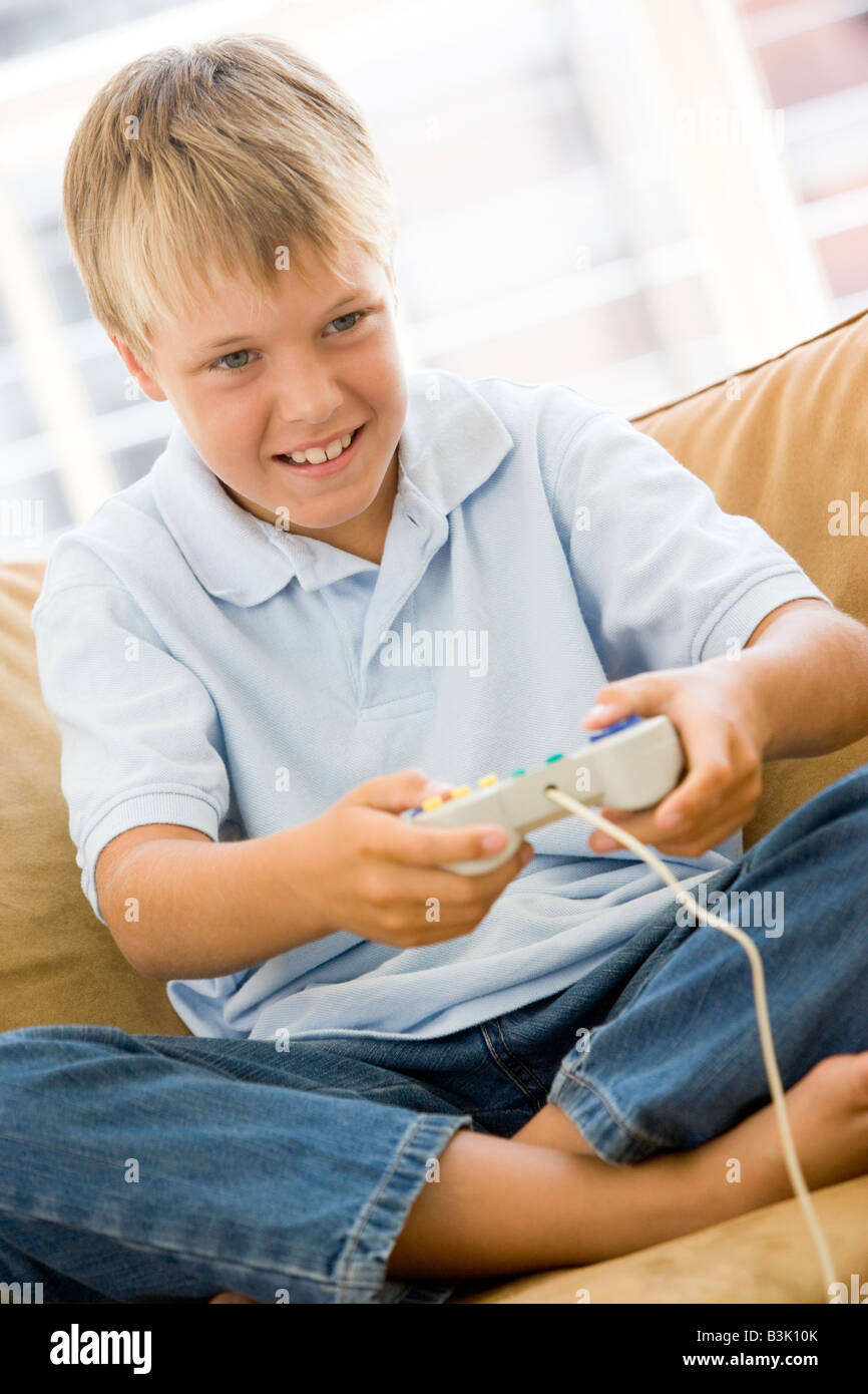 Joven en la sala de estar con video game controller sonriendo Foto de stock
