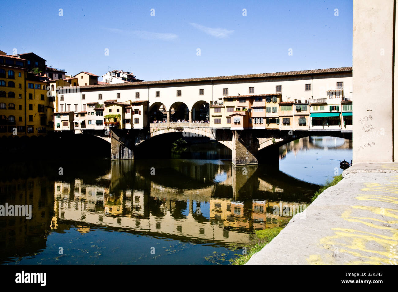 El Ponte Vecchio, el puente antiguo que es una calle comercial a través del fiume Arno Foto de stock