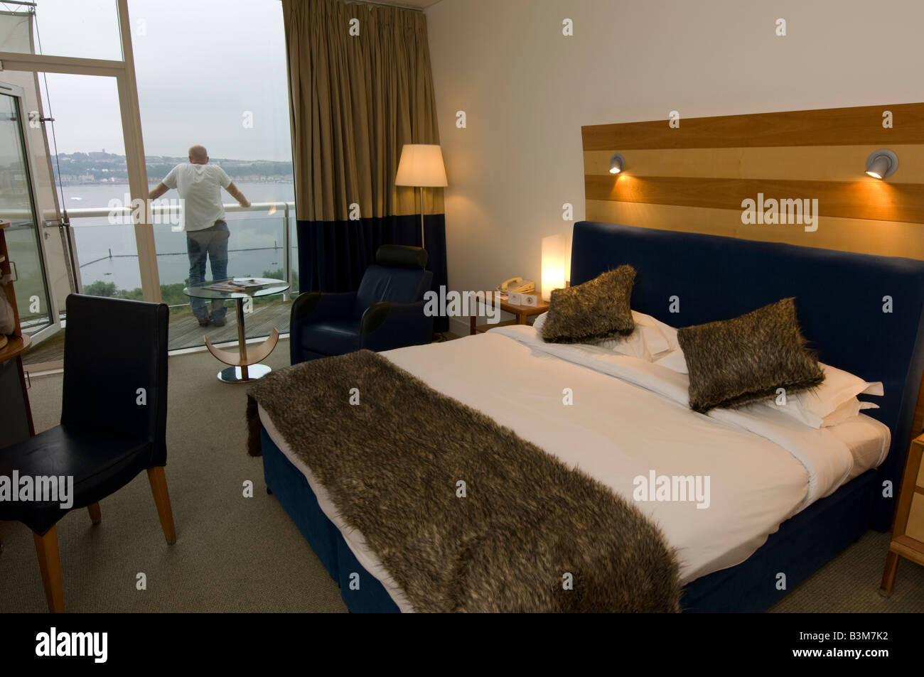 Las habitaciones del St Davids hotel 5 estrellas de lujo en la bahía de Cardiff, Gales, Reino Unido - El hombre de pie en el balcón mirando a la vista Foto de stock