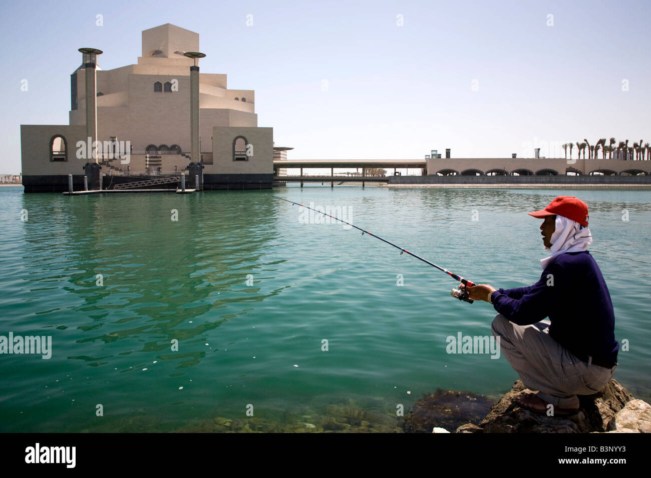 Hombre de pesca con los antecedentes del nuevo museo de arte islámico en la Bahía de Doha Doha Qatar Oriente Medio Golfo Arábigo Skyline Foto de stock