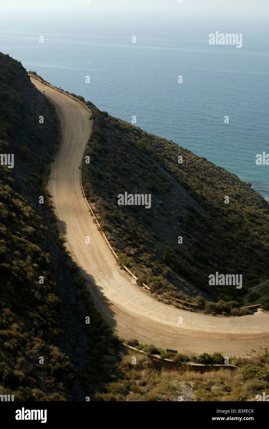 Montaña costera grava dirt track con ocean detrás en formato vertical que ofrece el automovilismo y conceptos de vacaciones en la costa en la UE Foto de stock