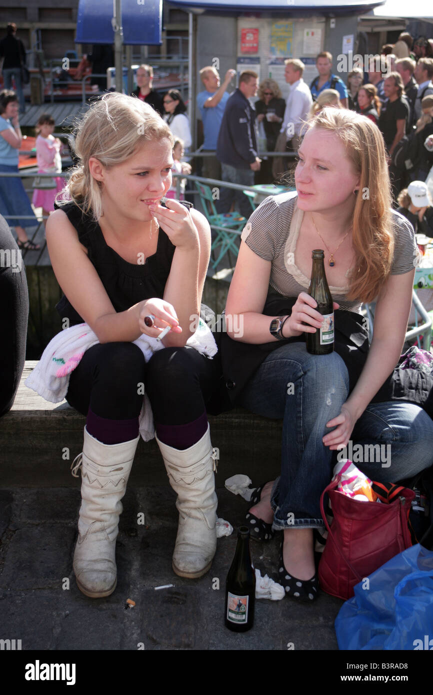 Dos niñas relajante con una botella de cerveza canalside Copenhague Dinamarca Foto de stock
