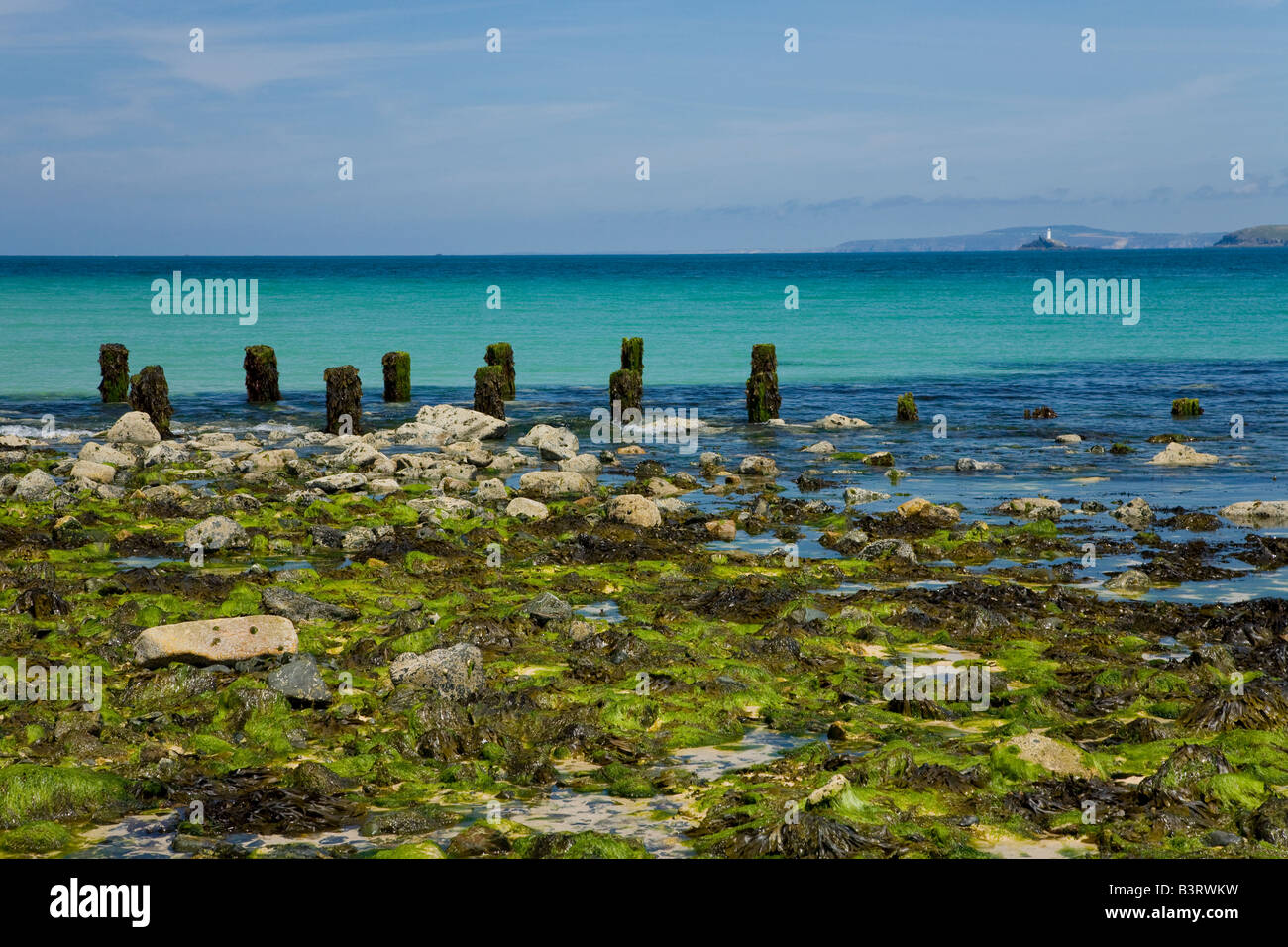 Vista a través de Carbis Bay al faro de Godrevy St Ives en verano el sol en la marea baja Cornwall West Country Inglaterra GB Foto de stock