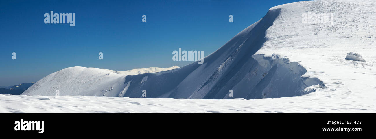 Montañas invernales ridge con saliente de nieve y snowboard caps las pistas de fondo de cielo azul Foto de stock