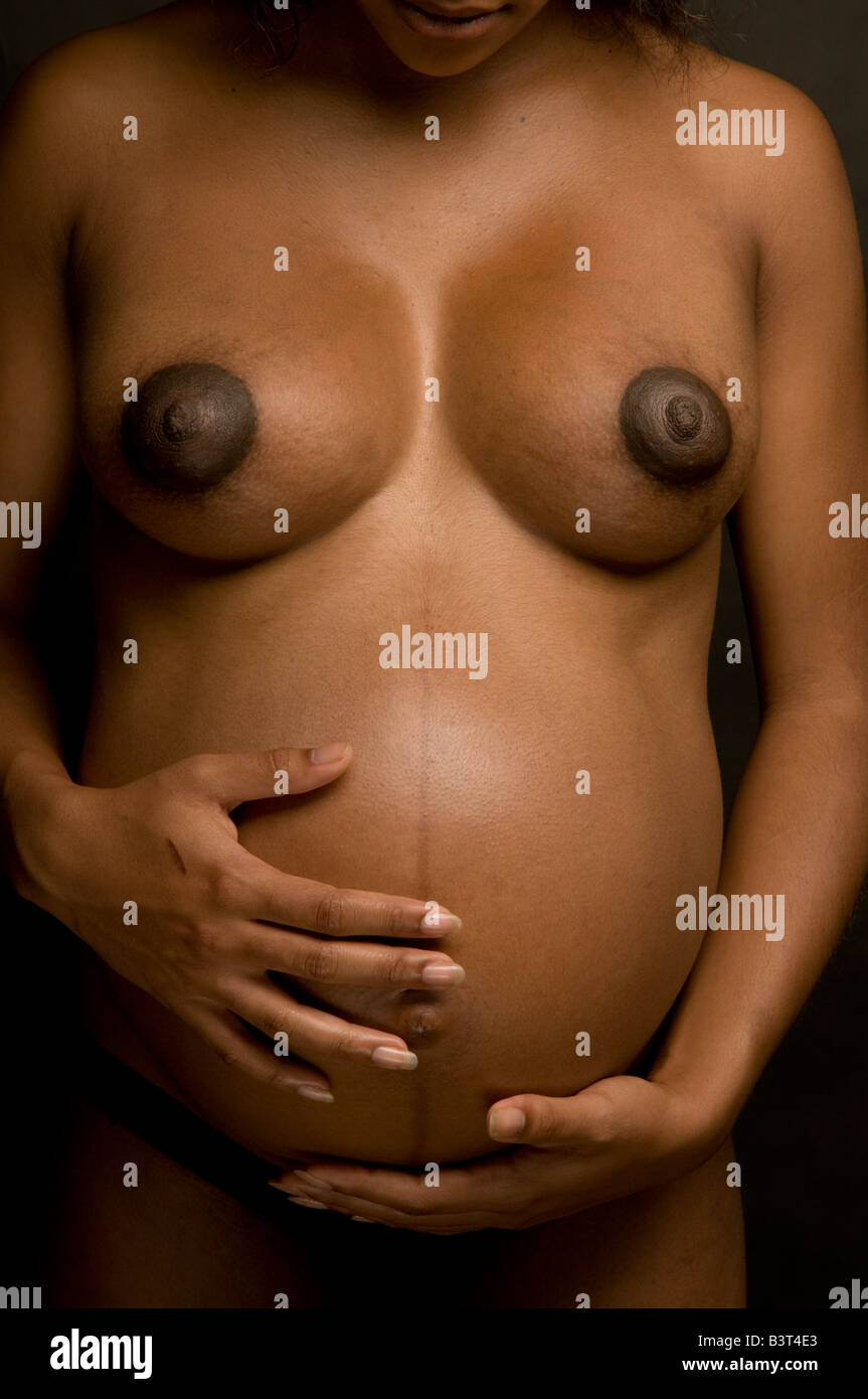 Desnudo negro nude afro-caribeña joven chica embarazada de 7 meses, el  vientre hinchado y lleno los senos, sosteniendo el vientre en sus manos  Fotografía de stock - Alamy