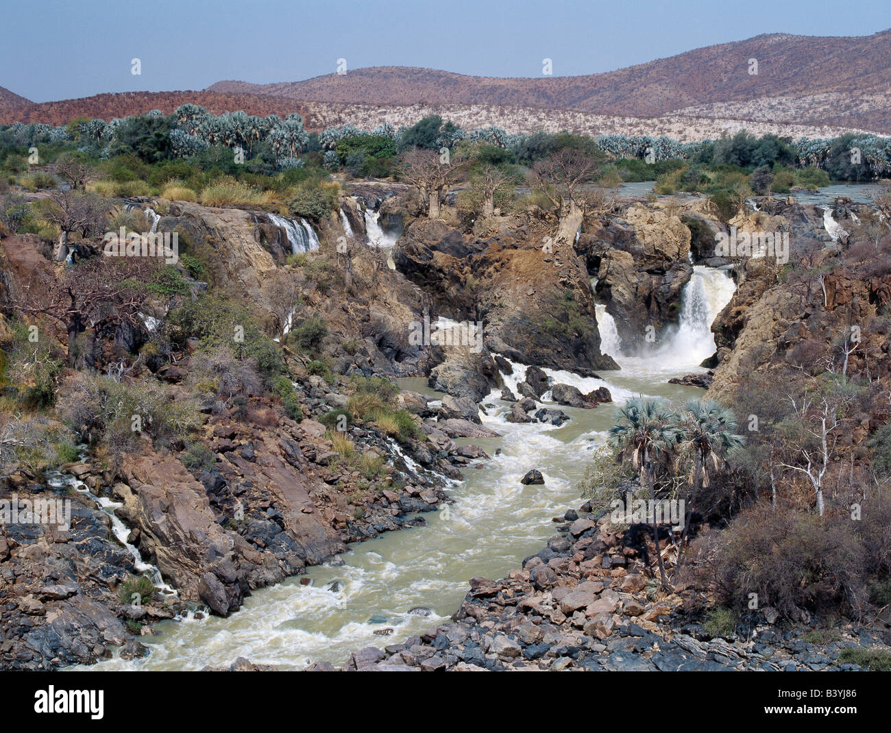 Namibia, Kaokoland, Epupa. La atractiva Epupa Falls en el accidentado noroeste de Namibia son una serie de canales paralelos, donde el río Kunene desciende a 60 metros en un kilómetro y medio. En esta remota región, el río forma la frontera entre Angola y Namibia. "Epupa' en el idioma Herero local significa 'Falling Waters'. Foto de stock