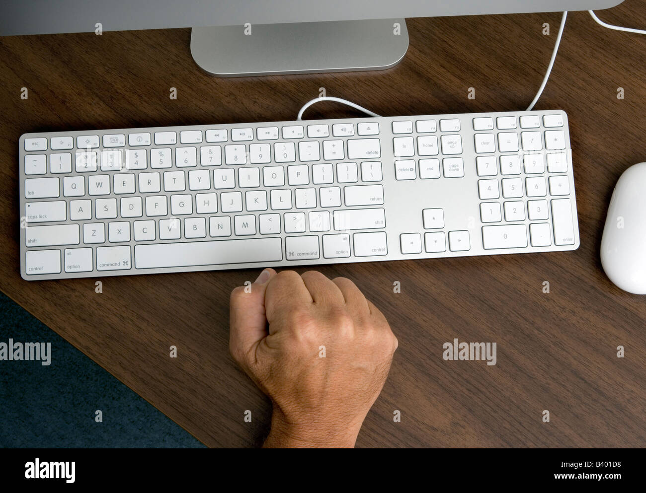 Un autor en el ordenador con bloque de escritores clenches su puño como él se sienta frustrado por la incapacidad para pensar en la palabra correcta. Foto de stock